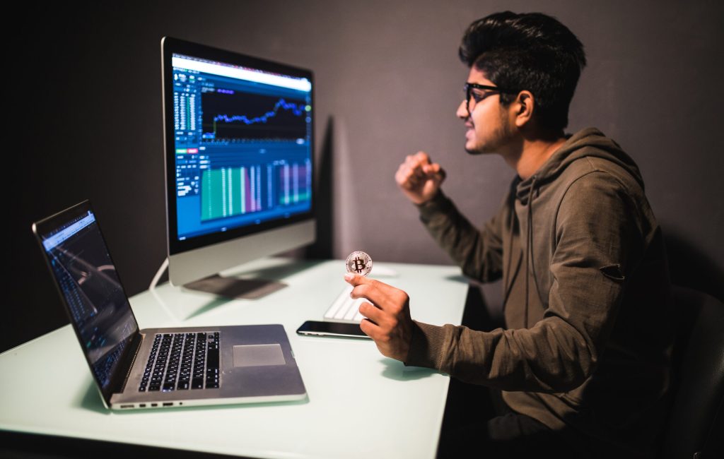 Indian trader checking stock trading data analysis concept working in office with financial graph on computer monitors