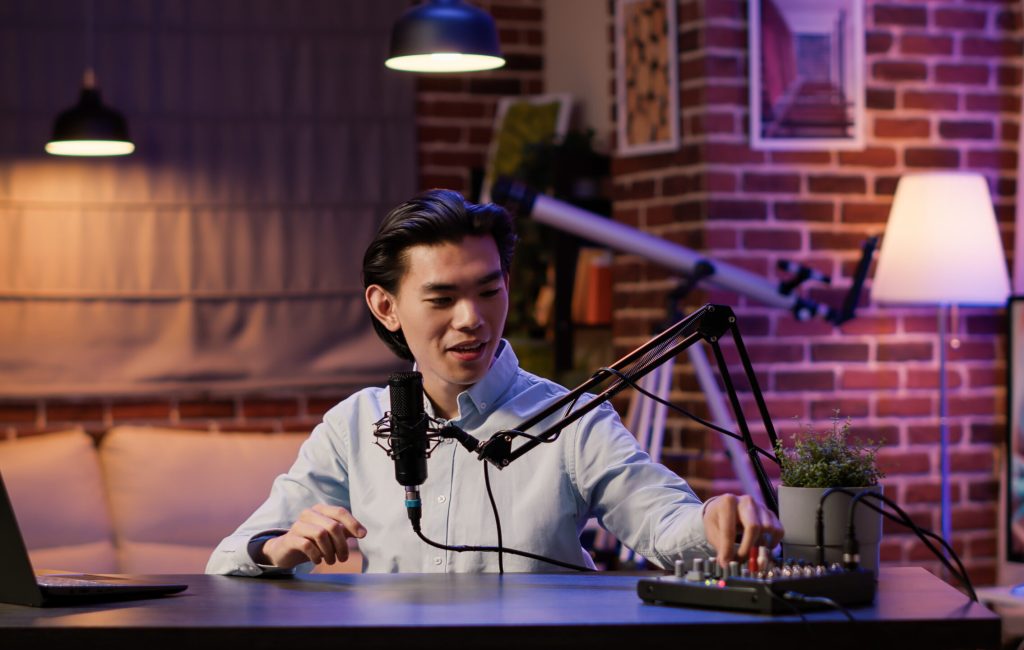 Male vlogger live broadcasting podcast episode on camera, using audio equipment. Creating content for social media channel and recording talk show video, web production. .