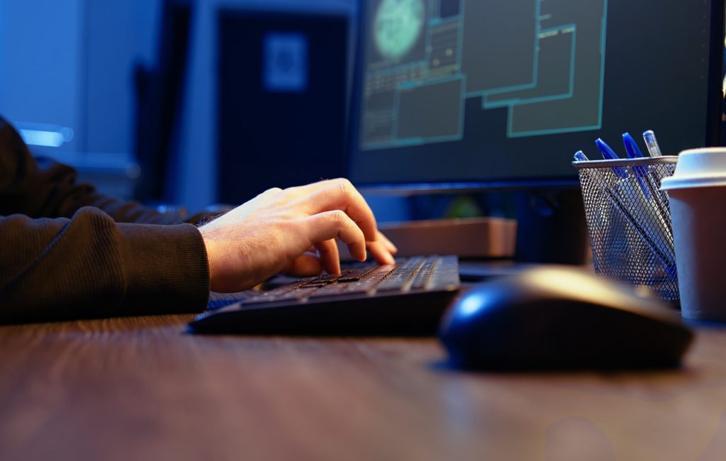 Meticulous hacker typing on computer keyboard, doing data breaches and financial theft in dark bunker. Close up shot on cybercriminal stealing users bank account credentials, camera A